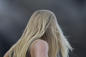 Blond long-haired young lady woman watching the surfers at Morro